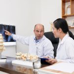Chiropractors analyzing spine x-ray on the wall