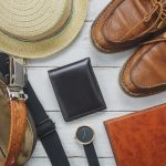 Top view accessoires to travel with man clothing concept. wallet on wooden background.watch,bag,hat,notebook and shoe on white wood table.